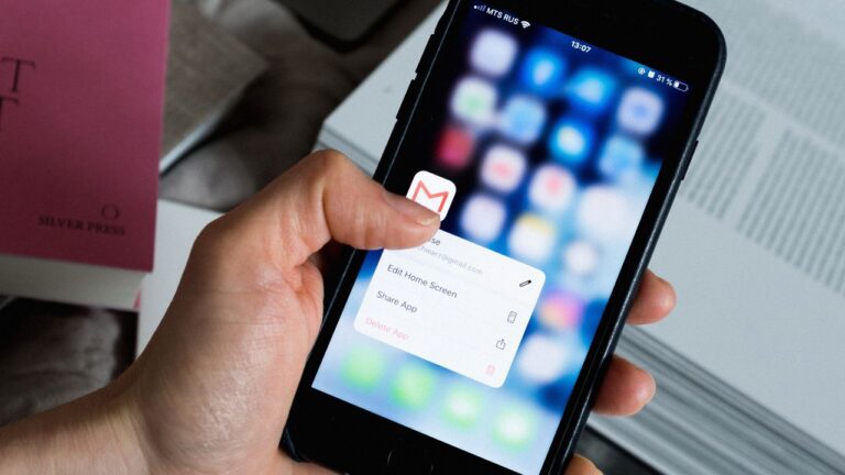 Hand holding a smartphone with an email app open, representing dental email marketing campaigns