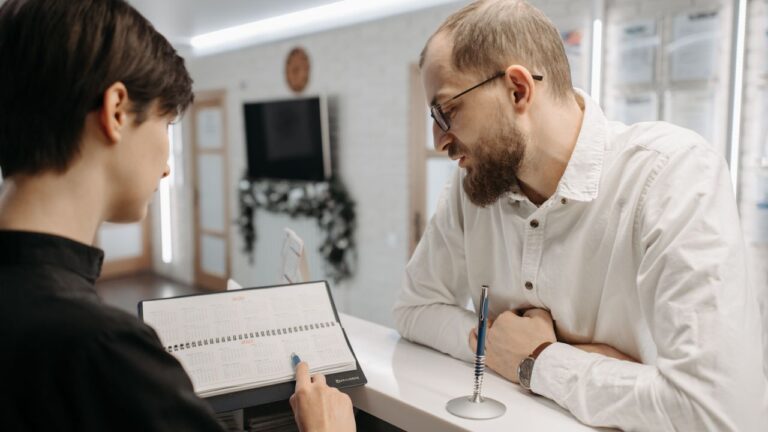 Clinic receptionist and patient reviewing appointments at the front desk, illustrating Dentrix CRM integration